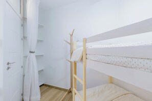 Et værelse med køjeseng, en hvid dør med gardin og et flisegulv.