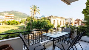 A balcony with a table and chairs, a view of a building, and a palm tree. - Kyparissia Modern Home Serene Views Calm Vibes (Trifylia)
