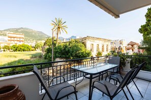 Ein Balkon mit Tisch und Stühlen, Blick auf ein Gebäude und eine Palme.