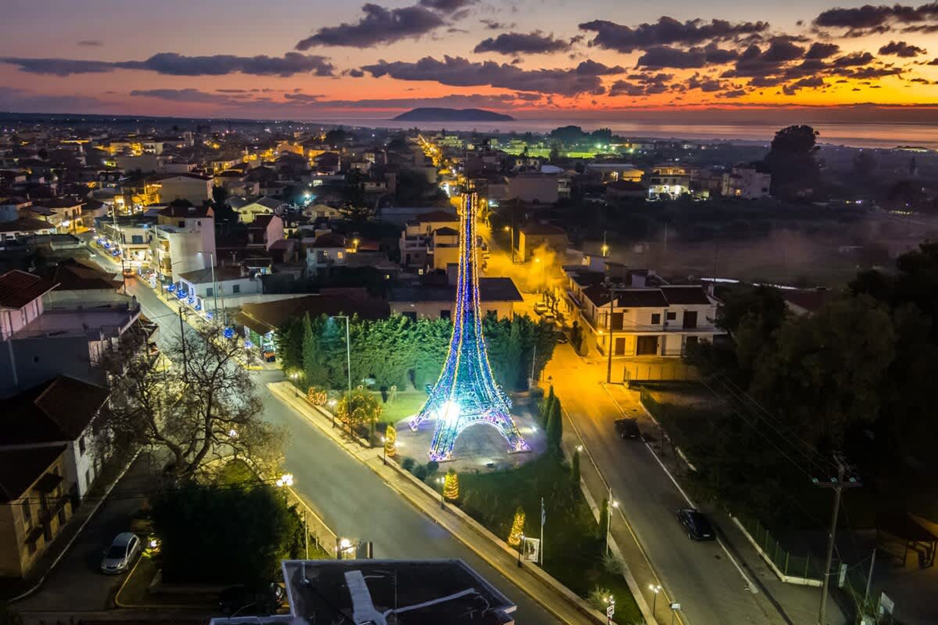 A cityscape with a prominent illuminated tower, likely a landmark, surrounded by residential buildings and a road.