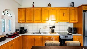 A kitchen with wooden cabinets, a stainless steel sink, a stove, and a refrigerator. - Kyparissia Modern Home Serene Views Calm Vibes (Trifylia)