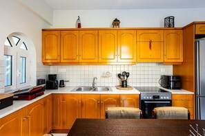 Eine Küche mit Holzausstattung, einer Edelstahl-Spüle, einem Herd und einem Kühlschrank.