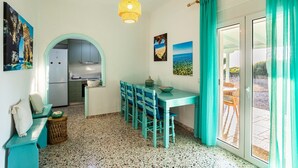 Una cucina con armadi, un frigorifero e un'area pranzo con sedie e tavolo.