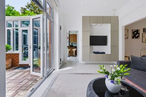 Ein modernes Wohnzimmer mit einer Couch, einem Couchtisch und einem an der Wand befestigten Fernseher.