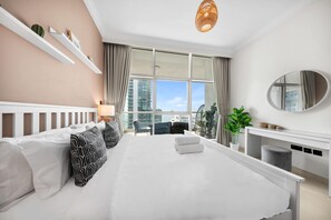 A modern hotel room with a large bed, a desk, and a view of the city. - Free Housekeeping Visits During Your Stay - Stayshort - Elegant 4 Bedroom in Dubai Marina That Sleeps 10 (Dubai)