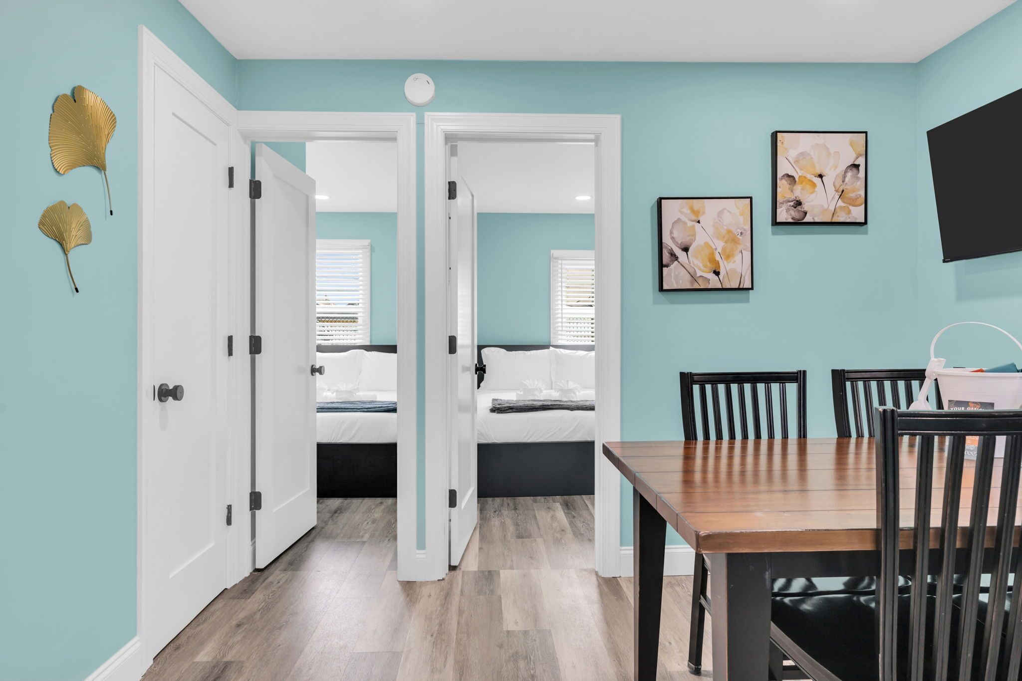Una habitación con cama, una mesa de comedor con sillas y un televisor montado en la pared.