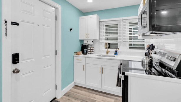 A modern kitchen with white cabinets, a stainless steel range, and a built-in oven.