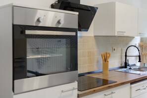 Eine moderne Küche mit Backofen aus Edelstahl, einer Holz Arbeitsplatte und einem schwarzen Wasserhahn.