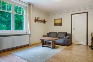 Ein Zimmer mit Fenster, einer Couch, einem Tisch und einem Bild an der Wand.