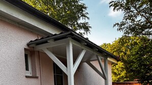 A house with a covered porch, a door, and a brick pathway leading to the entrance. - Apartment 'Idylle Ostsee' – Buddenhagen, Gateway to Usedom Island (Wolgast)