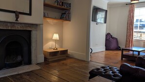 A living room with a fireplace, a lamp, a television, and a bean bag chair. - Spacious three bedroom house with garden, close to O2, quick to central London (London)