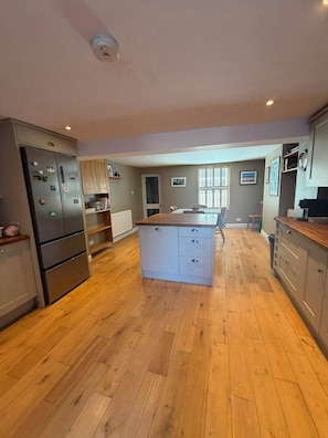 A spacious kitchen with wooden flooring, a central island, and built-in appliances. - Spacious three bedroom house with garden, close to O2, quick to central London (London)
