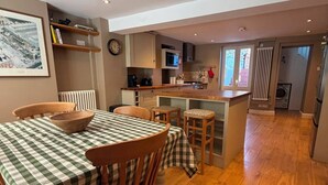 A spacious kitchen with wooden flooring, a dining area with a checkered tablecloth, and a view of the outside. - Spacious three bedroom house with garden, close to O2, quick to central London (London)