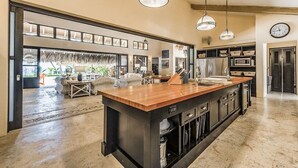 A spacious kitchen with a central island, pendant lighting, and a view into the dining area. - Beachfront Paradise  Pool & Staff  (Sosúa)