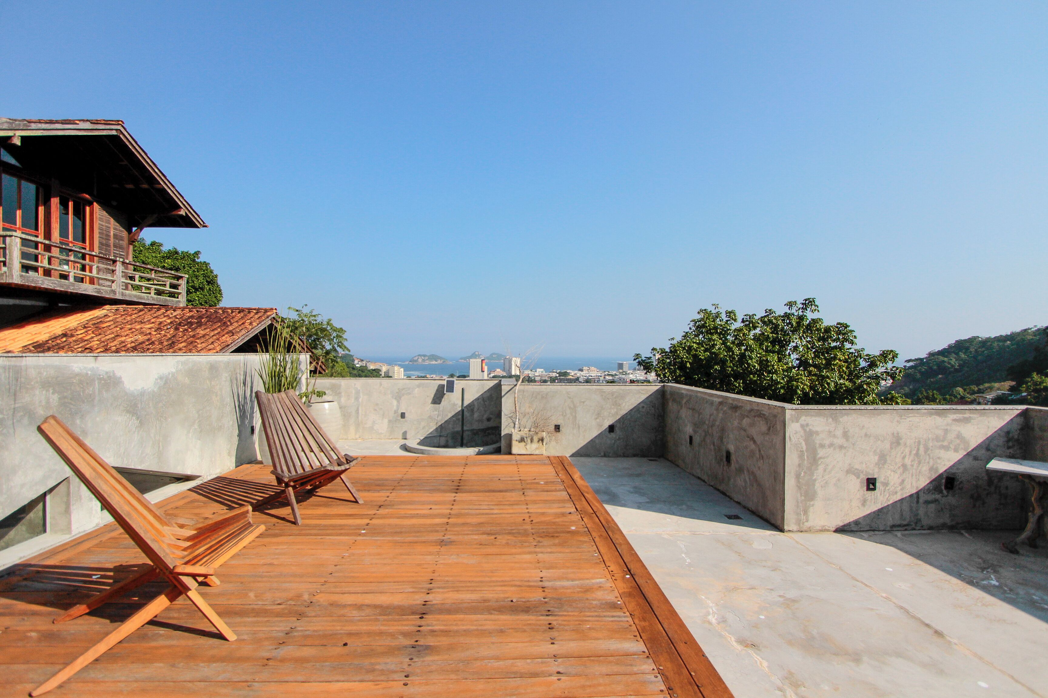 Eine Dachterrasse mit Holzboden, einer Liege und Blick auf die Skyline.