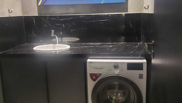 Een kleine keuken met een wasmachine en een spoelbak.
