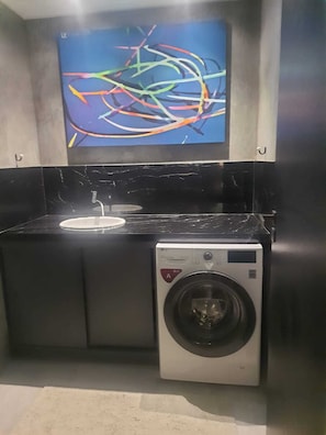 A compact kitchen with a washing machine and a sink. - Emerald Penthouse, serene, mysterious, under the spell of the Tijuca Forest. (Rio de Janeiro)