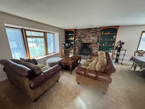 Ein Wohnzimmer mit Ledersofas, einem Couchtisch, einem Kamin und einem Bücherregal.