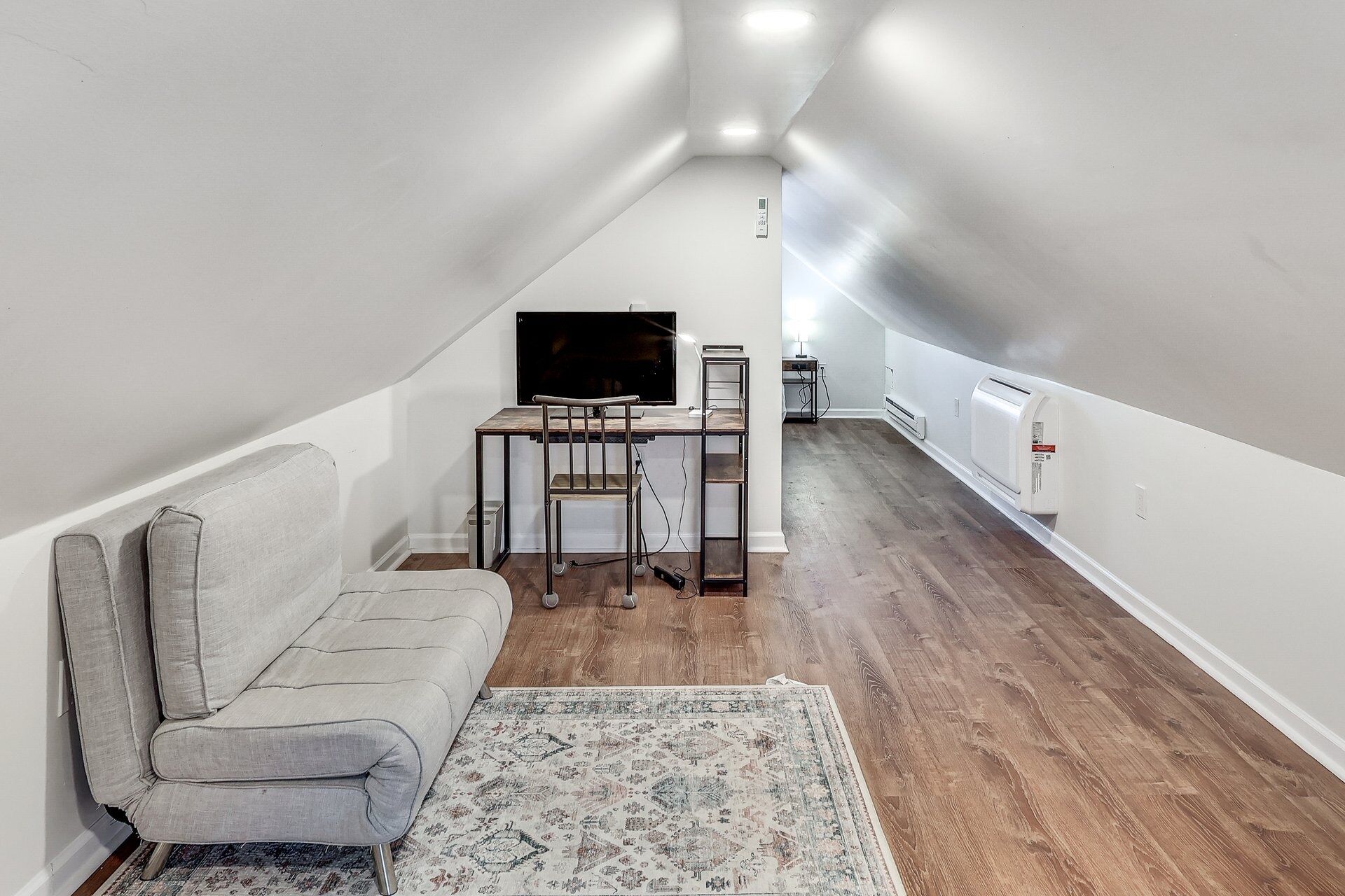 Un espacio habitable compacto con sofá, televisor, una mesita y un radiador.