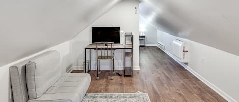 A compact living space with a sofa, a TV, a small table, and a radiator.