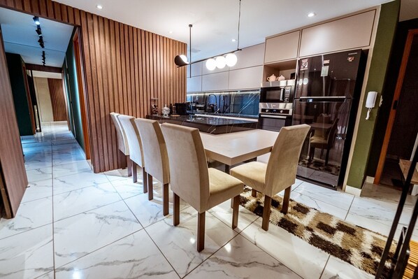 A modern kitchen with a central island, built-in appliances, and a dining area with chairs. - Apartment with Pool, Gym and BBQ Area (João Pessoa)