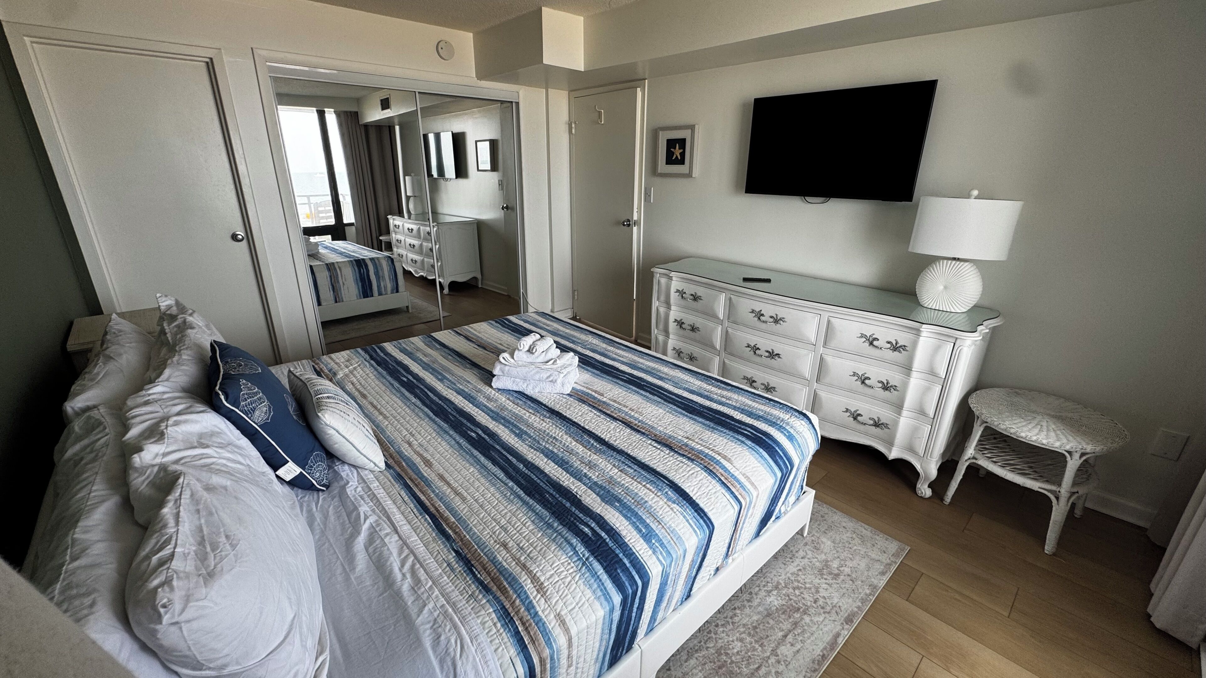 Une chambre à coucher avec un lit, une commode, une télévision et un miroir.
