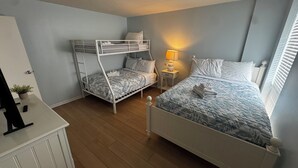 Une chambre avec deux lits superposés, une table de chevet avec une lampe et une commode.