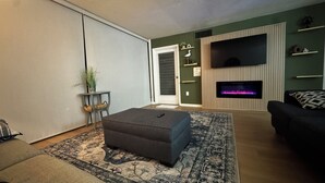 Un salon avec une cheminée, un canapé, une table basse et un téléviseur.