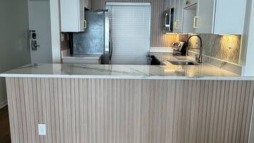 A modern kitchen with a central island, built-in appliances, and a herringbone-patterned backsplash.