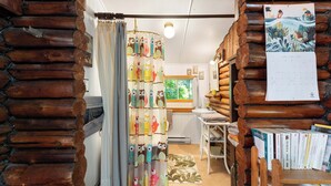 Habitació acollidora amb paret de fusta, cortina amb motius d'úls, un calendari i una estanteria plena de llibres.