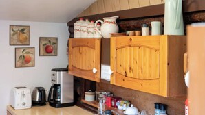 Una cuina amb armaris de fusta, una cafetera, un torradora i diversos objectes de cuina sobre el taulell.