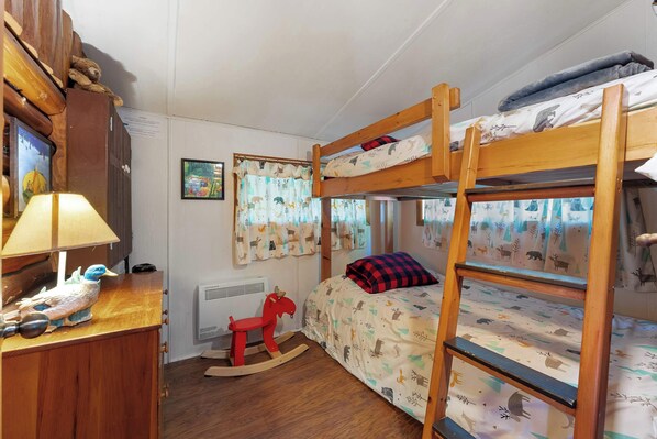 A child's bunk bed room with a rocking horse, a desk with a lamp, and a window with curtains.