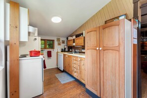 A compact kitchen with wooden cabinets, a white refrigerator, and a red pot on the stove.