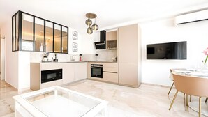 A modern kitchen with a built-in oven, a coffee machine, and a dining area with a glass table.