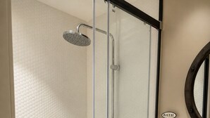 A glass-enclosed shower with a handheld showerhead and a wall-mounted faucet. - Yamila (Barcelona)