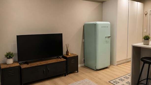 A modern kitchen with a flat-screen TV, a light blue refrigerator, and a wooden cabinet. - Yamila (Barcelona)