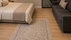 A bedroom with a bed, a nightstand, a lamp, a sofa, a rug, and a wall clock. - Yamila (Barcelona)
