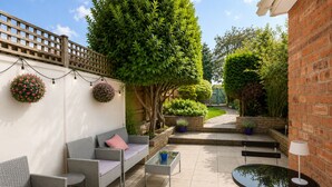 An outdoor patio with wicker furniture, a table, and potted plants. - The Willow Chester | Parking | Canal Walks | Large Garden | Sleeps 8 (Chester)