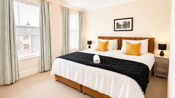 A hotel room with a large bed, two bedside tables, a chandelier, and a framed picture on the wall.