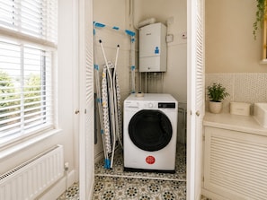 Une buanderie équipée d’un lave-linge à chargement frontal, d’un étendoir et d’un radiateur.