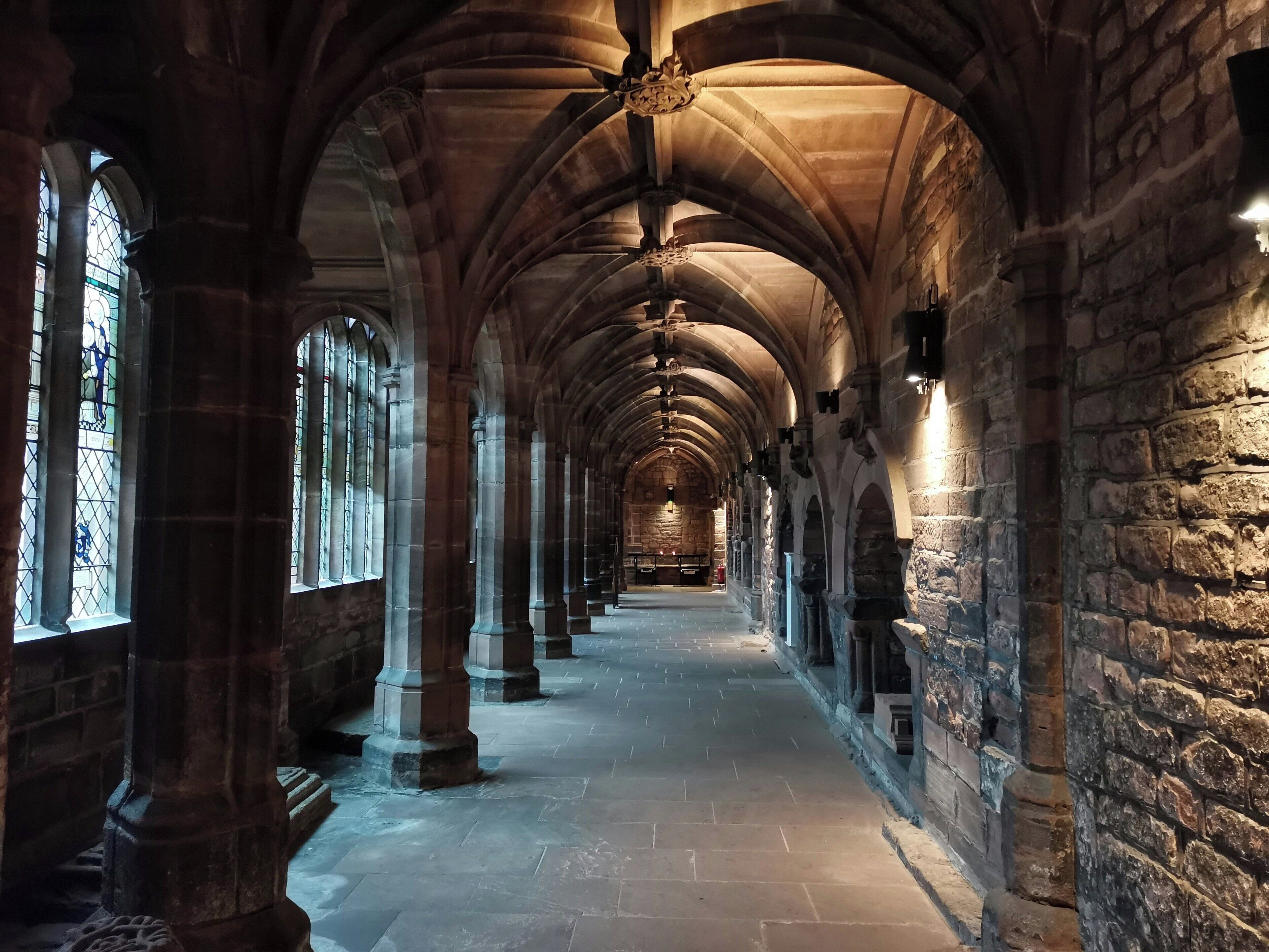 A long corridor with stone columns and arches, leading to a distant end.