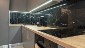Ett modernt kök med mörka skåp, en backsplash i marmor och en svart spishäll.