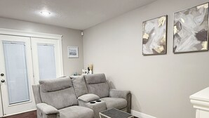 Un soggiorno con un divano grigio, un tavolino, un tappeto decorato e opere d'arte astratte alle pareti.