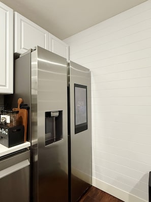 A stainless steel refrigerator with a digital display, a coffee machine, and a wooden cutting board. - Cozy Two-Level Basement Suite - Kitchen & Laundry (Orem)
