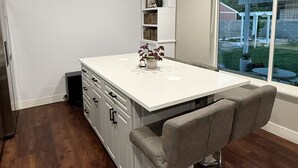 Una cucina moderna con isola centrale, sgabelli da bar e una finestra che offre vista sull'esterno.
