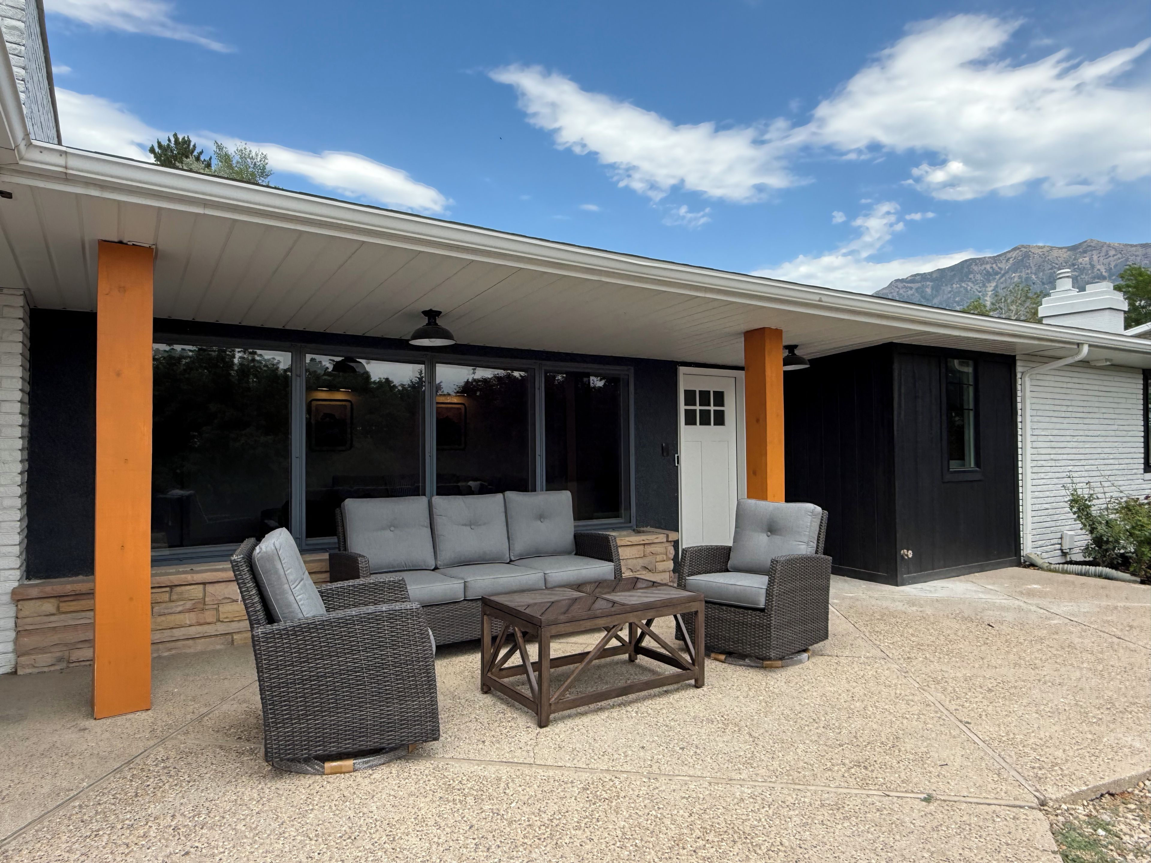 A covered patio area with a sofa set, two chairs, and a coffee table.