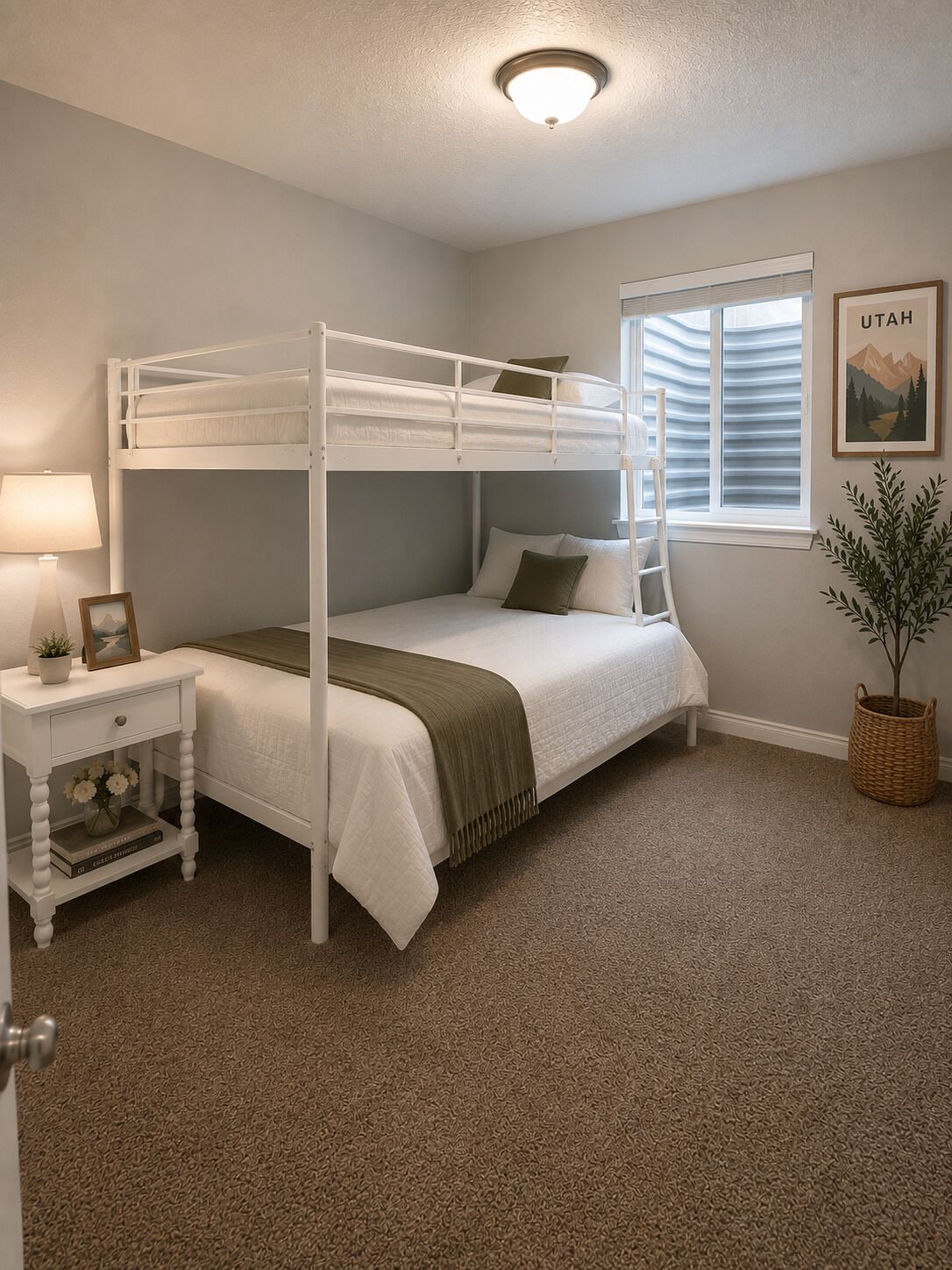 A bunk bed room with a window, a bedside table with a lamp, and a framed picture.