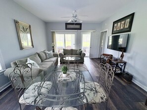 Ein Wohnzimmer mit Glastisch, Sofas und Fernseher.
