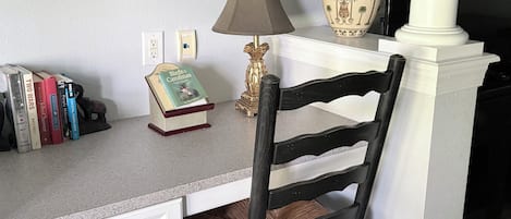 Un escritorio con una lámpara, un jarrón y libros.