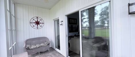 A covered porch with wicker furniture, a ceiling fan, and a sliding glass door leading to a patio.